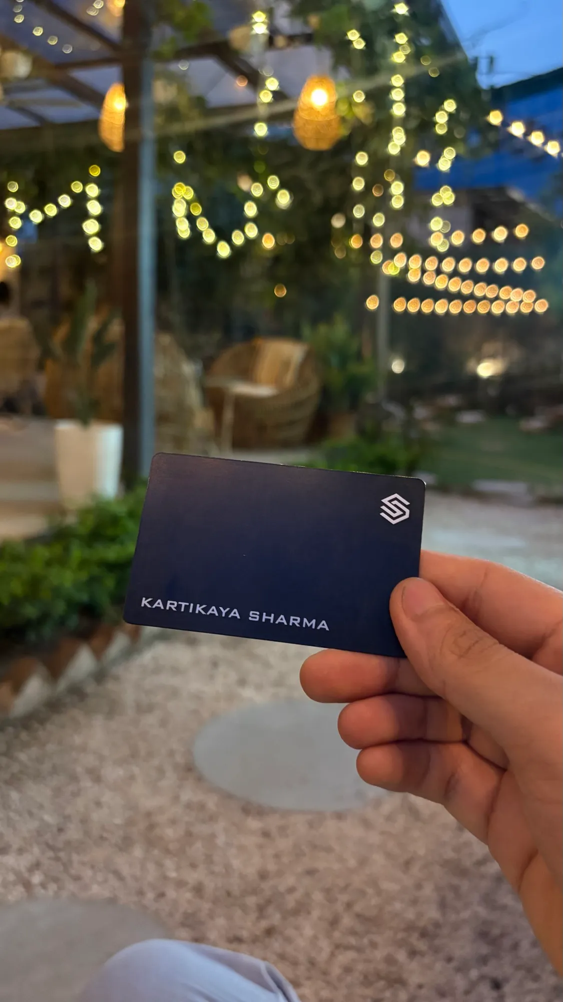 Holding a matte black BLACKCARD NFC business card under warm string lights