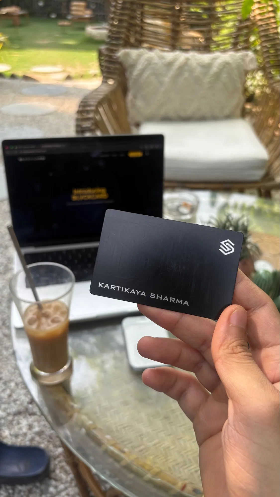 BLACKCARD NFC business card held at a cafe with a coffee and laptop
